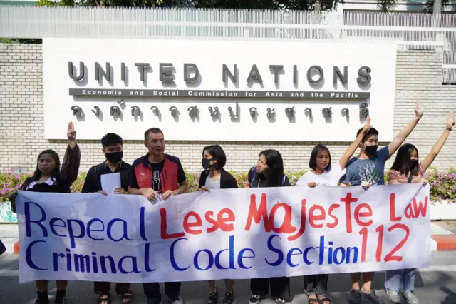 ผู้ประท้วงชูป้ายเรียกร้องยกเลิกกฎหมายมาตรา 112