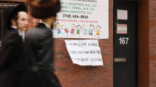 Di signboard outside one doctor office for America dey warn pipo wey get measles make dem no near im door