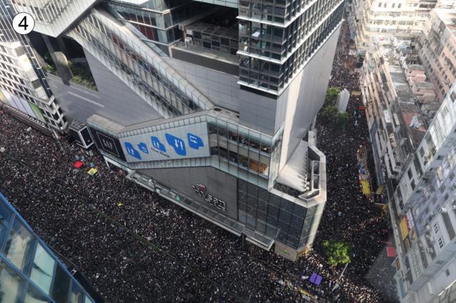 This shot from a building rooftop shows a converging V-shaped junction at the corner of a building - and huge crowds stretching off in either direction, even off the main route
