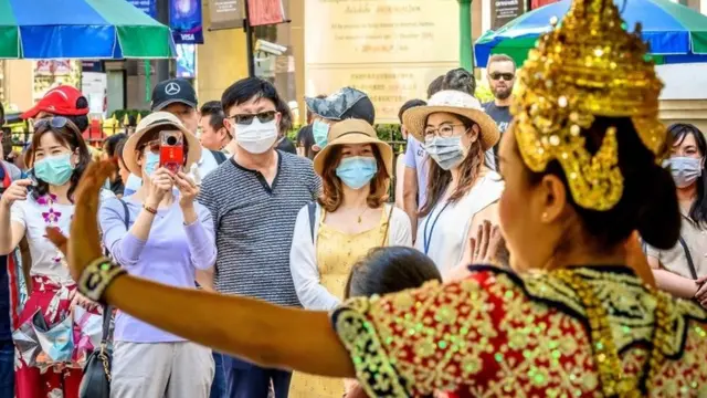 Chinese tourists with face masks watch a traditional Thai dance at Erawan shrine, a popular spritual landmark in Bangkok on January 27, 2020.