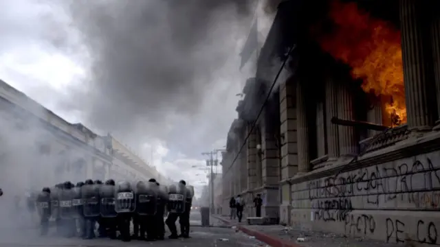 Parte de la sede del Congreso de Guatemala en llamas con policías antimotines en frente