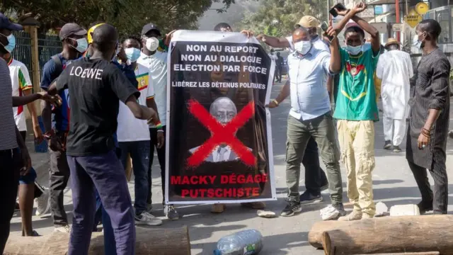 Des manifestants déploient une banderole sur laquelle on peut lire "Macky, putschiste, dégage" lors d'une manifestation à Dakar, Sénégal - 9 février 2024.