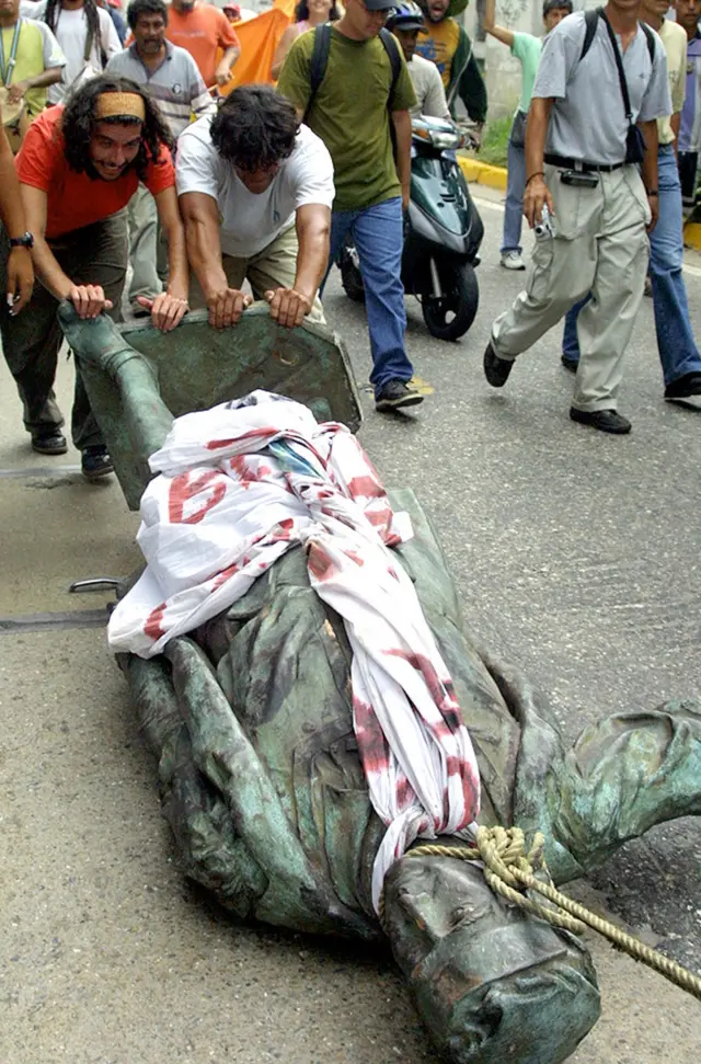 Varias personas arrastra la estatua de Colón