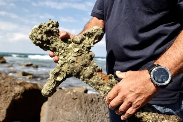Yaakov Sharvit of the IAA holds a sword believed to have belonged to a Crusader who sailed to the Holy Land almost a millennium ago after it was recovered from the Mediterranean seabed by an amateur diver, the Israel Antiquities Authority said, Caesarea, Israel October 18, 2021.