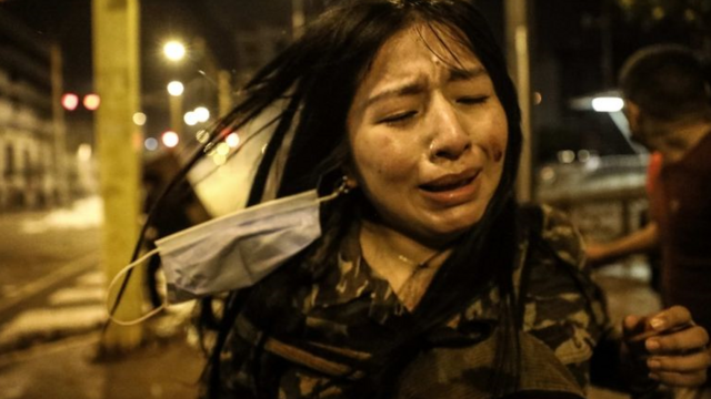Em foto noturna, mulher chora em meio a manifestação na rua