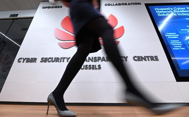 A woman walks past a logo at the entrance of the European Huawei Cyber Security Transparency Centre during its opening in Brussels on March 5, 2019.