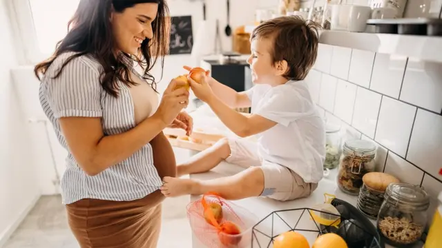 Una madre embarazada con su hijo en la cocina.