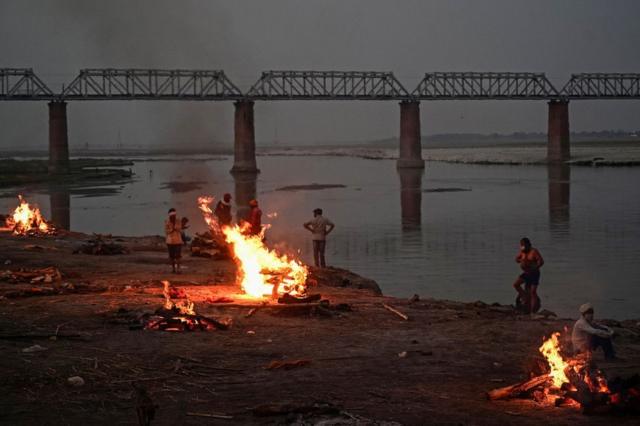 Funeral pyres are lit by the Ganges in Allahabad - bodies have been washing up downstream for days