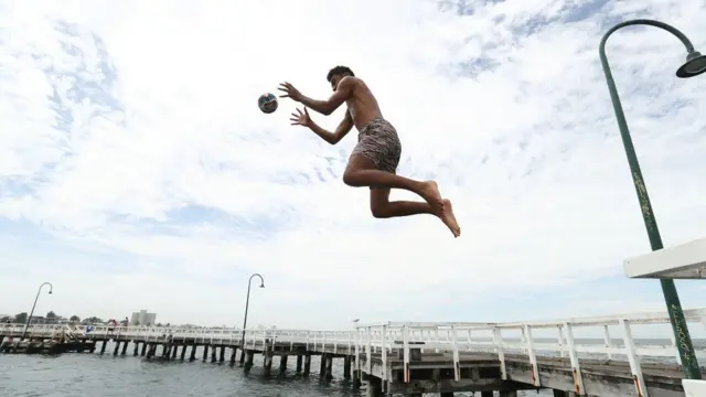 مرد جوان در حال پریدن داخل آب در بندر ملبورن