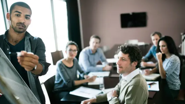 Un hombre da una presentación ante sus colegas en una junta de reuniones.