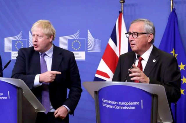 Boris Johnson gestures towards Jean-Claude Juncker during their address in Brussels