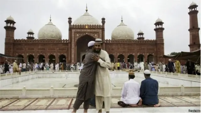 नमाज़ पढ़ते और गले मिलते लोग