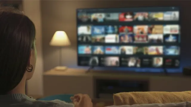 Женщина перед экраном телефизора с видео по требованию