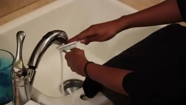 Woman wey dey wash her tools.