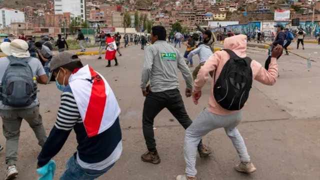 Manifestantes lanzando piedras contra la policía en Cusco.