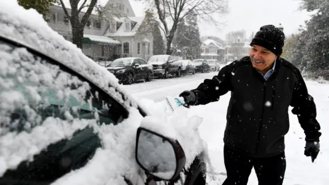 Чоловік чистить машину від снігу