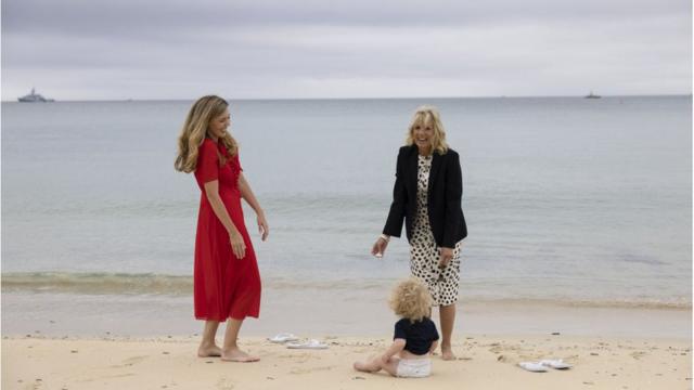 拜登夫人和約翰遜夫人在卡比斯灣的沙灘上脫掉鞋子在海灘陪伴約翰遜夫婦的兒子。