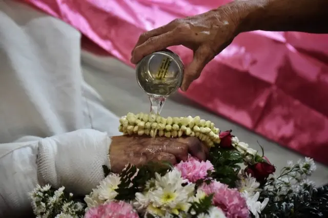 มือของผู้เสียชีวิตขณะถูกรดน้ำศพ