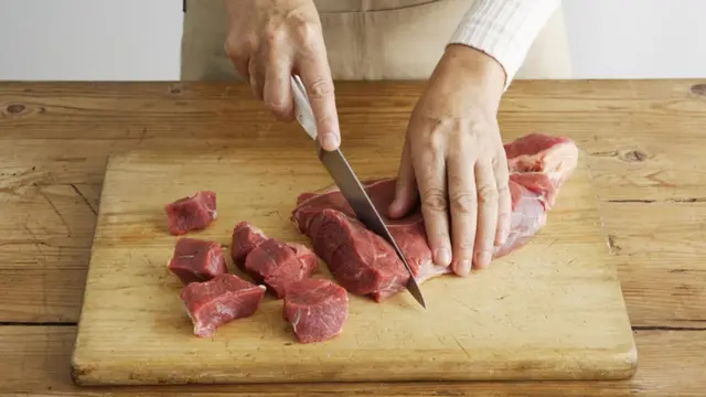 Pessoa corta carne vemelha numa tábuabetano boas vindasmadeira