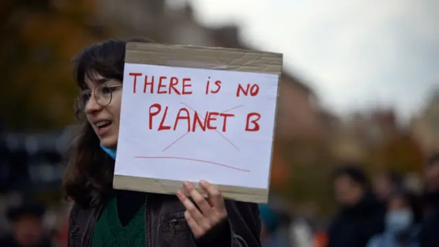 Une jeune femme tient une feuille "Il n'y a pas de planète B" lors d'une marche pour le climat à Toulouse, en France, en 2021.
