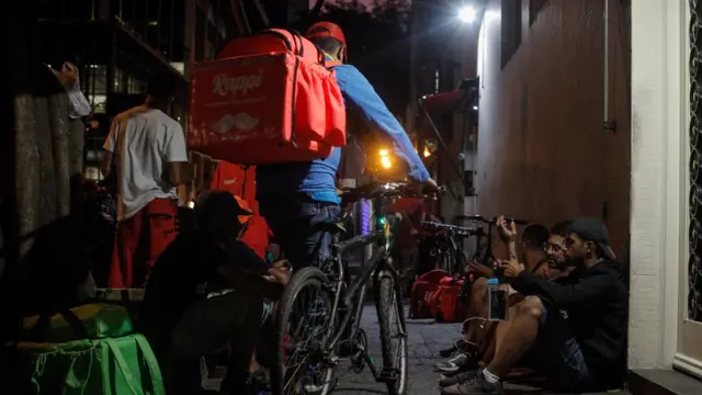 Na região da rua Augusta, centro de São Paulo, entregadores de aplicativos aguardam pedidos em calçada