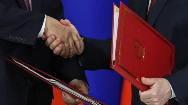 हाथ मिलाते हुए शी जिनपिंग और पुतिन