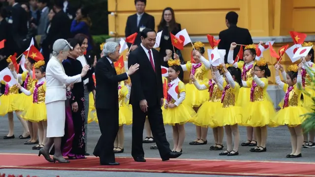 Japan's Emperor Akihito (2nd R) waves to children waving flags as he walks next to Vietnamese President Tran Dai Quang (1st R), Japan's Empress Michiko (L) and Quang's spouse Nguyen Thi Hien during an official welcoming ceremony at the presidential palace in Hanoi on March 1, 2017. Japan's emperor and empress departed February 28 for their first trip to Vietnam to meet families of former Japanese soldiers to help heal wounds left over from its occupation of the country during World War II.