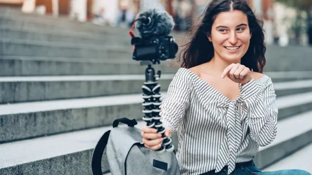 Una joven se enfoca con una cámara.