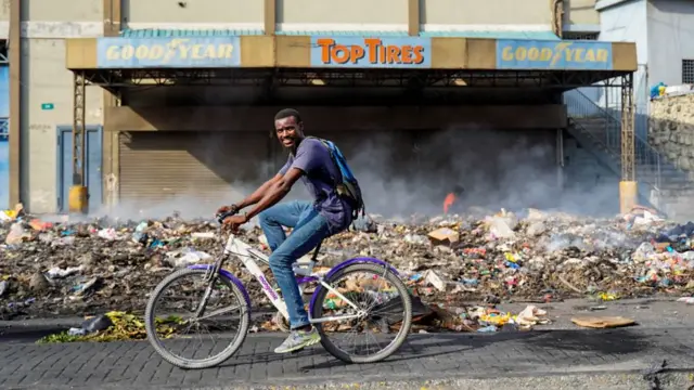 Un hombre en bicicleta frente restos de un saqueo