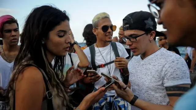 Jovens olham seus telefones no Malecón,banca que da bonus no cadastroHavana