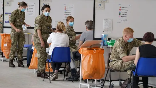 Des membres des forces armées administrent des vaccins au centre de vaccination du centre sportif régional de Ravenscraig à Motherwell, en Écosse, le vendredi 11 juin 2021