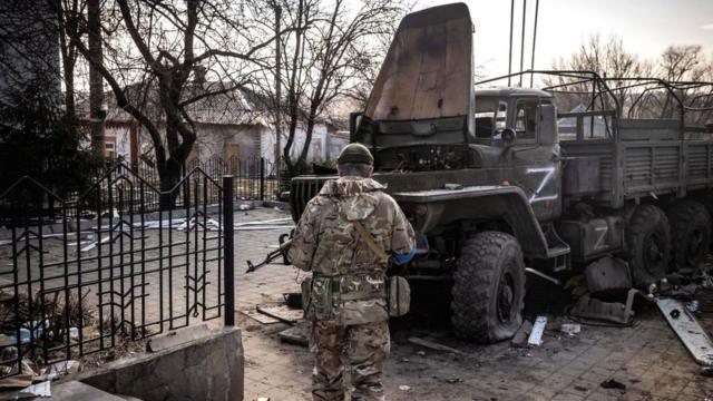 A Ukrainian serviceman stands near a Russian army truck in the north-eastern city of Trostianets