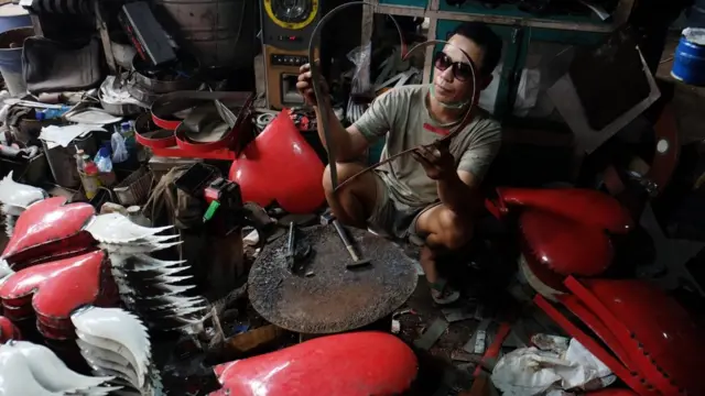 Perajin membuat kerajinan aksesoris berkarakter hati dengan bahan baku tong bekas di Pasar Kabangan Solo, Jawa Tengah, Sabtu (28/03)