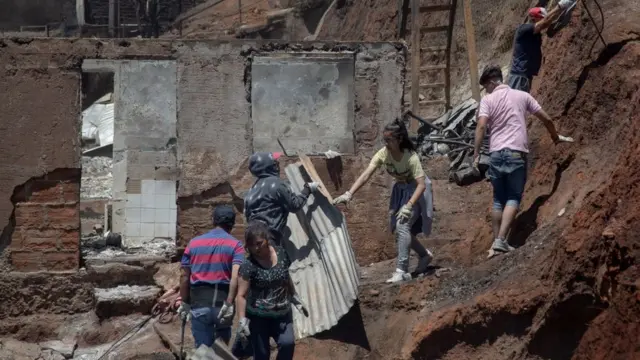 Vecinos y bomberos en la zona afectada por el fuego.