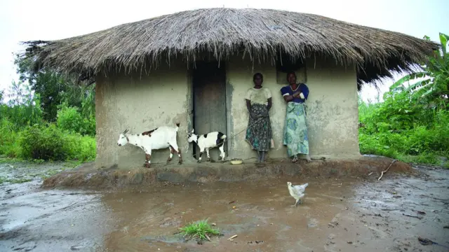 People stand for outside dia house to escape flooding