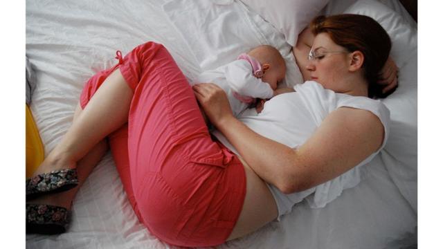 Mãe dormindo ao lado da filha bebê