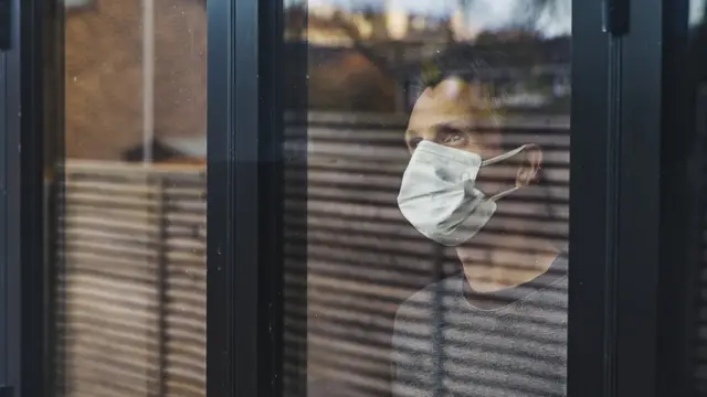 Человек в маске за оконным стеклом