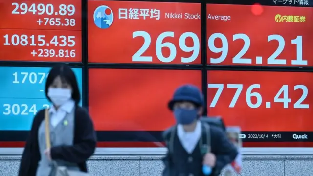 Personas caminando con pizarras mostrando la bolsa en Japón