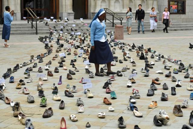 راهبة كاثوليكية من زامبيا تسير وسط مئات الأحذية التي وضعت أمام كاتدرائية وَستمنستر الأربعاء، كجزء من عمل فني للتنويه بحملة البابا فرانسيس لدعم اللاجئين