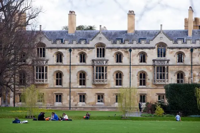 นักศึกษานั่งบนสนามหญ้าในมหาวิทยาลัย