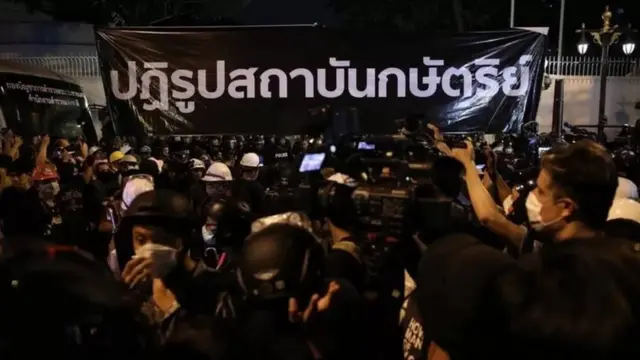 ผู้ชุมนุมกลุ่ม "ราษฎร" ถือป้ายเรียกร้องปฏิรูปสถาบันกษัตริย์