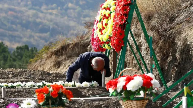 নিহত এক আর্মেনিয়ান সৈন্যের কবরে শোক প্রকাশ করছেন এক ব্যক্তি