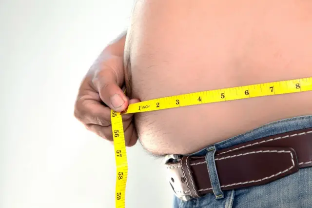 Hombre midiéndose la panza.