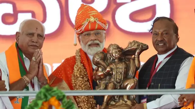 नरेंद्र मोदी मंच पर बजरंग बली की मूर्ति स्वीकार करते हुए. प्रधानमंत्री नरेंद्र मोदी अपनी रैलियों में बजरंग बली का नारा लगा रहे हैं