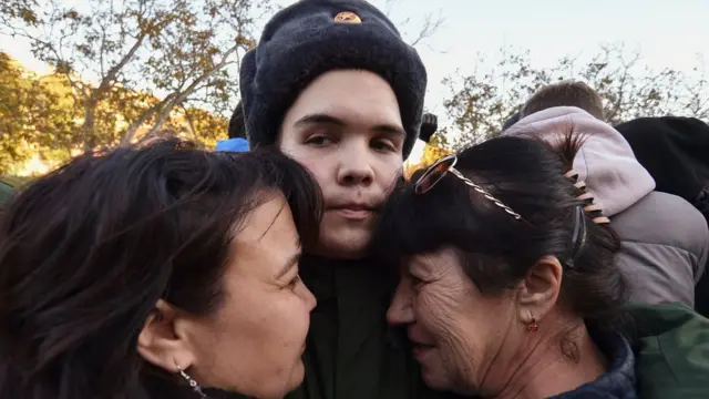 A Russian conscript bids farewell to his relatives before he leaves to serve in the army at a railway station in Sevastopol, Crimea
