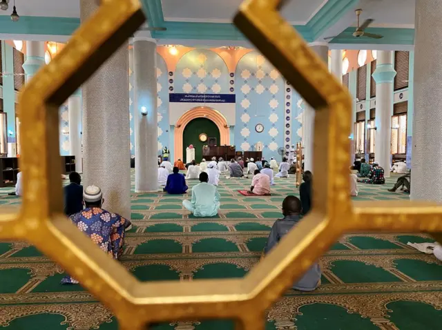 Worshippers sit inside and pray.
