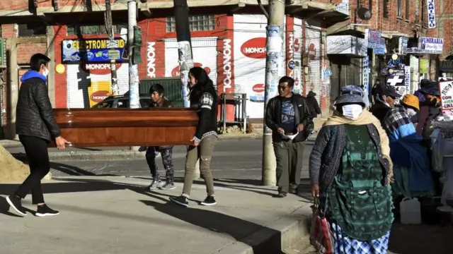 Dos personas cargando un ataúd en El Alto.