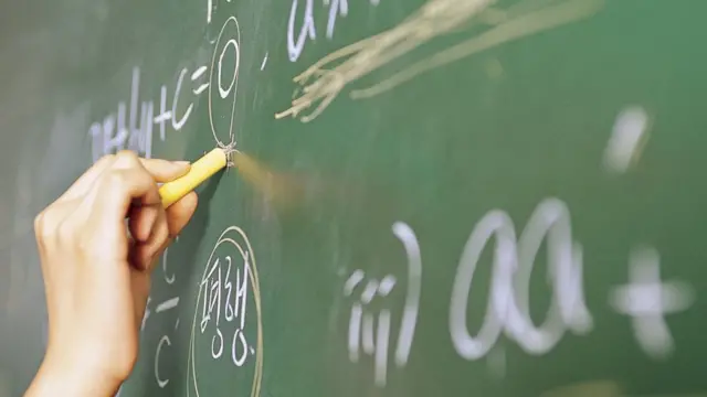 Mano escribiendo en un pizarrón.