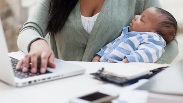 Mulher com bebê trabalhando no computador