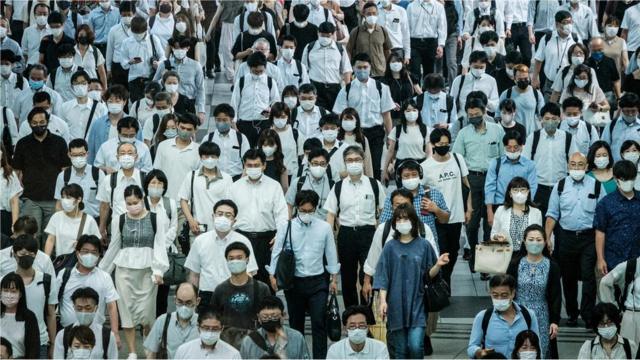 Multidão de passageiros de trem usando máscaras em Tóquio, no Japão
